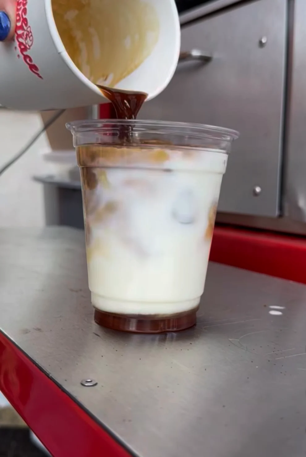 Espresso poured over milk and ice for an iced latte on Annie's steel counter