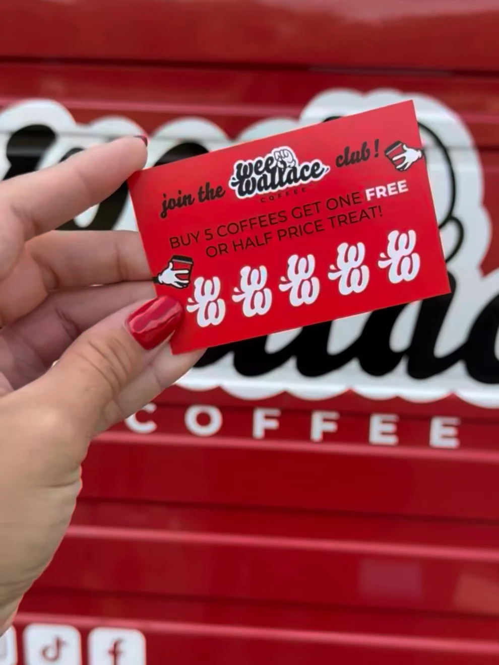 A hand with red nails holding a red Wee Wallace club loyalty card in front of Annie's logo