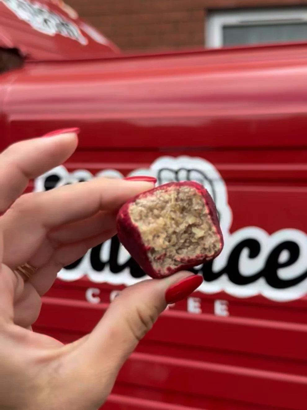 A bite-sized red-coated treat held up in front of Annie